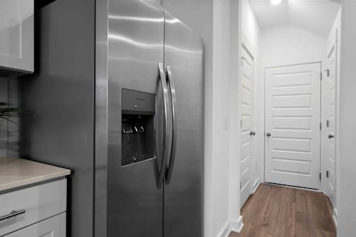 A modern kitchen with a stainless steel refrigerator and white cabinets.