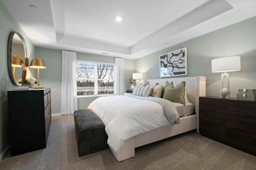 A bedroom with a large bed, a dresser, and a mirror.