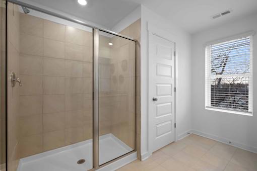 A bathroom with a walk-in shower and a white door.