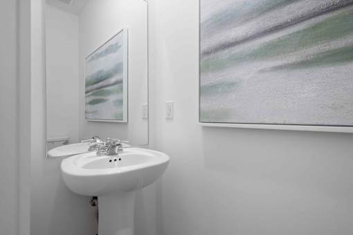 A white sink in a bathroom with a painting on the wall.