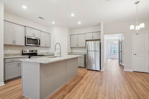 A kitchen with wooden floors and white cabinets.