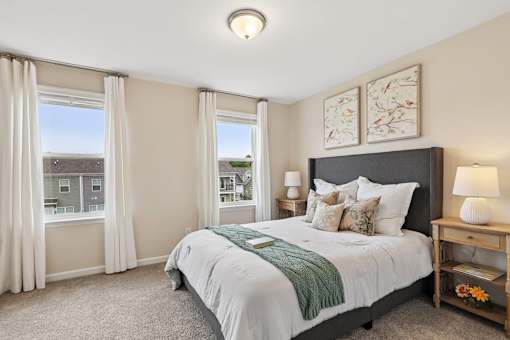A bedroom with a large bed and a window with curtains.