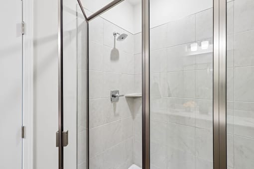 A shower area with a glass door and a shower head.