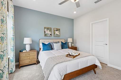 A bedroom with a large bed, two nightstands, and a ceiling fan.