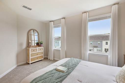 A bedroom with a large bed and a window with a view of buildings outside.