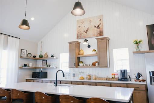 A kitchen with a white countertop and wooden chairs.