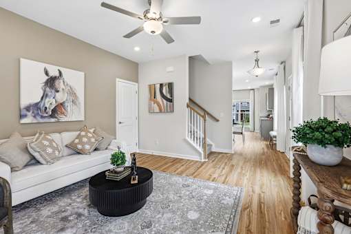 A living room with a white couch and a painting of a horse on the wall.