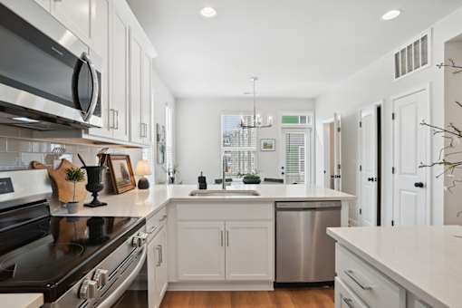 A modern kitchen with white cabinets and stainless steel appliances.