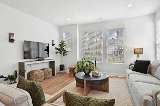 A living room with a white couch, a wooden coffee table, and a flat-screen TV mounted on the wall.