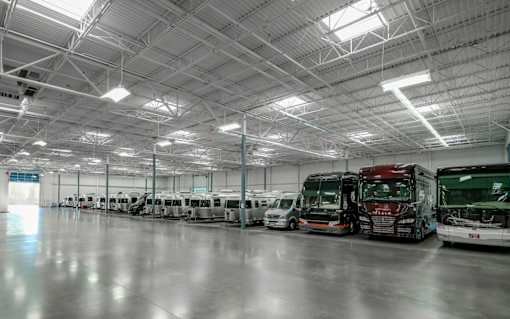 A large indoor space with several airstreams and diesel pushers parked inside