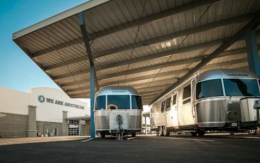 Two silver airsteams are parked under a covered space.