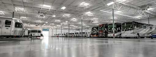 A large indoor space with several airstreams and diesel pushers parked inside.