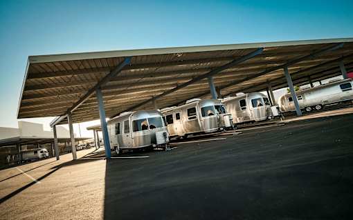 A row of airstreams are under a outdoor covered space.