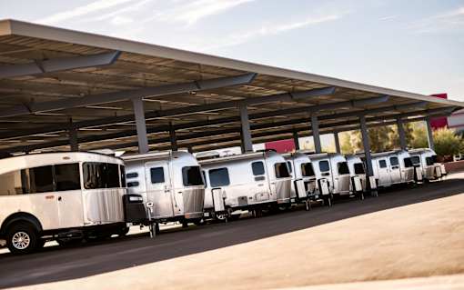 A row of silver airstreams are under an outside covered space.