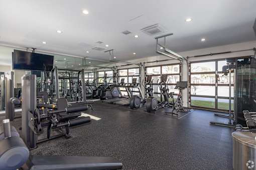 A gym with a variety of equipment including treadmills, weights, and exercise machines.