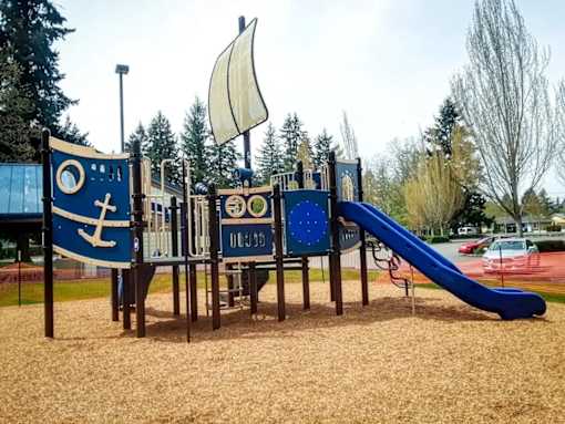 A playground with a slide and a wooden structure with a blue and white anchor design.