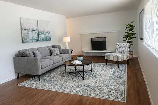A living room with a grey couch, a coffee table, a lamp, a fireplace, and a chair.