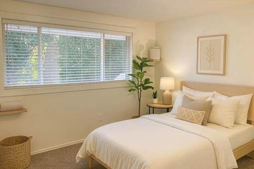 A bedroom with a large bed and a window with blinds.