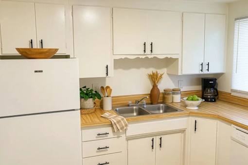 A kitchen with white cabinets and a wooden countertop.