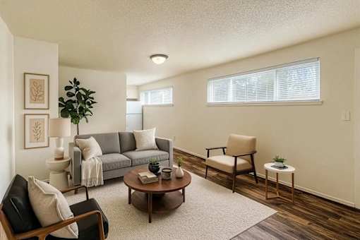A living room with a grey couch, a brown armchair, a wooden coffee table, and a potted plant.