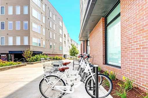 Two bicycles are parked next to a brick building.