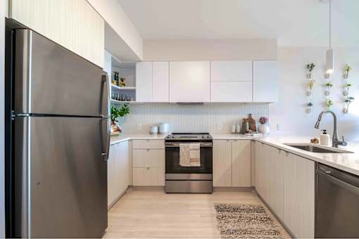 A modern kitchen with a refrigerator on the left and a sink on the right.