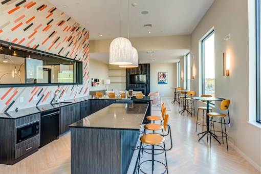 A modern kitchen with a bar area and orange chairs.
