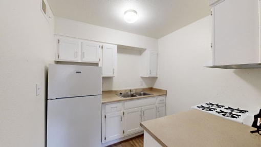 a kitchen with white cabinets and a refrigerator and a sink at La Terraza, Phoenix, 85018
