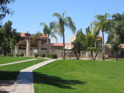 A building with a red roof is surrounded by palm trees.