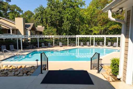 A pool surrounded by a white fence and a black mat.