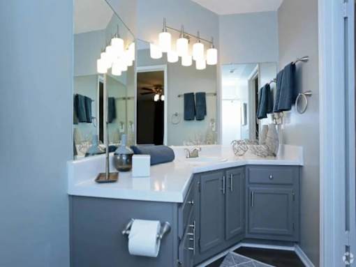 A bathroom with a white counter and grey cabinets.