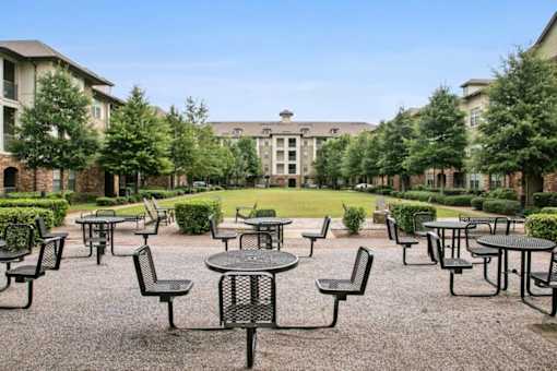 A courtyard with tables and chairs surrounded by buildings.