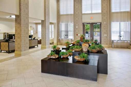 A long table with plants on it in a room with columns.