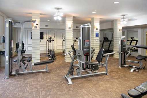A gym with a variety of equipment including treadmills, weights, and exercise machines.