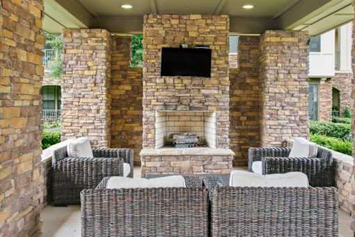 A patio with a fireplace and chairs.