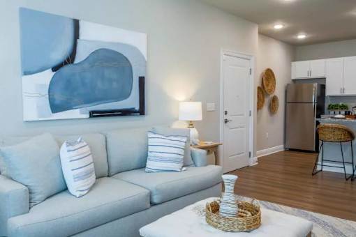 A living room with a grey couch and a painting on the wall.