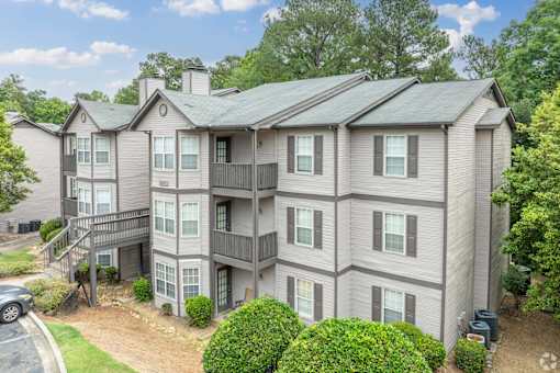 A large apartment complex with a car parked in the driveway.