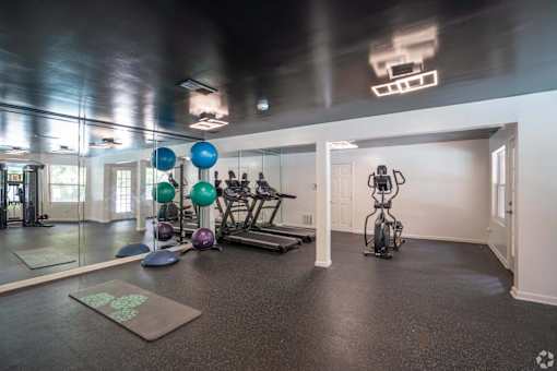 A gym with exercise equipment and a green logo on the mat.
