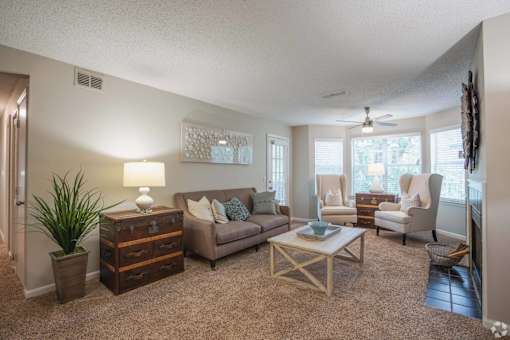 A living room with a brown couch, a coffee table, and a potted plant.
