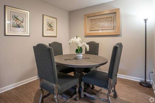 A dining room with a round table and four chairs.