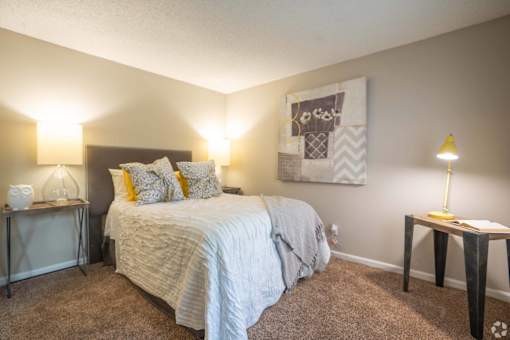 A bedroom with a bed, nightstands, and a lamp.