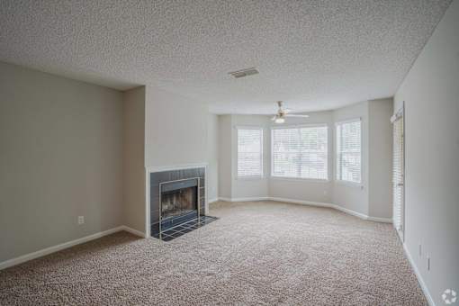 A living room with a fireplace and carpeted floor.