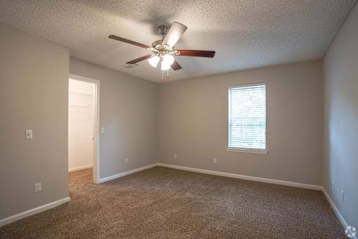 A room with a ceiling fan and carpeted floor.