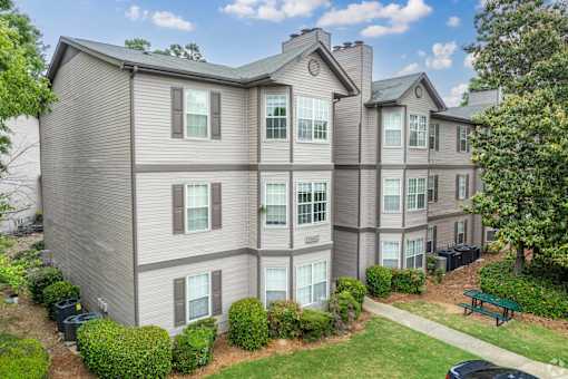 A large apartment complex with a green lawn and trees.