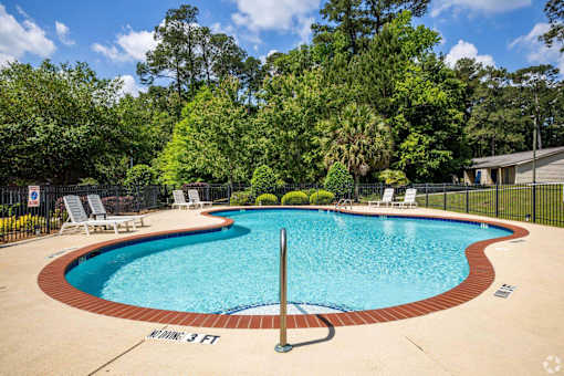 A small pool surrounded by a fence and trees.