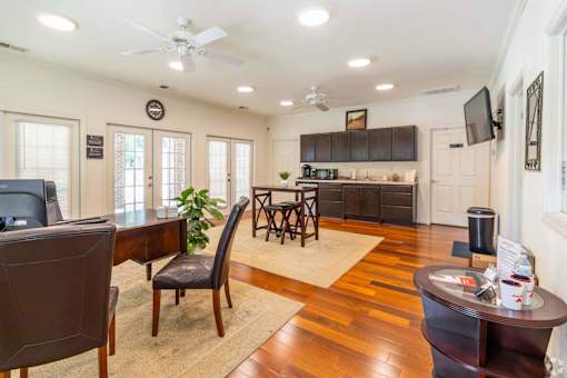 A well-lit room with a ceiling fan and a dining table with chairs.