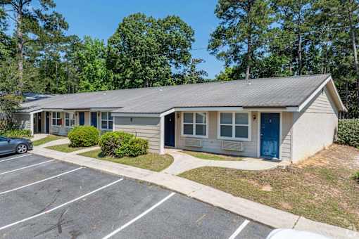 A small building with a blue door is surrounded by a parking lot.
