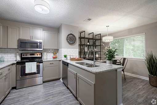 A kitchen with a stove, oven, microwave, and sink.
