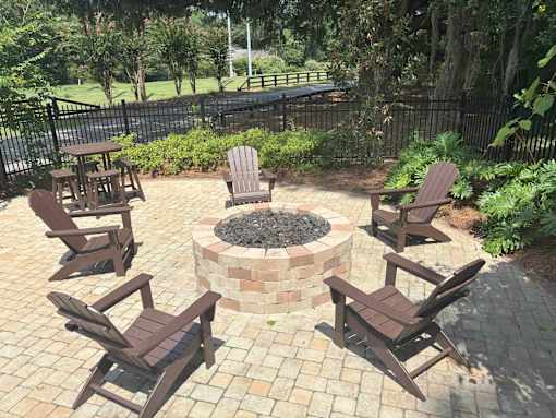 A fire pit surrounded by chairs in a backyard setting.