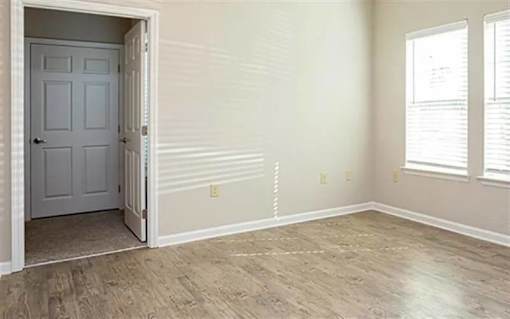 A room with a white door and wooden flooring.